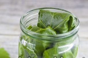 put cucumbers screwed into grape leaves at the bottom of the jar